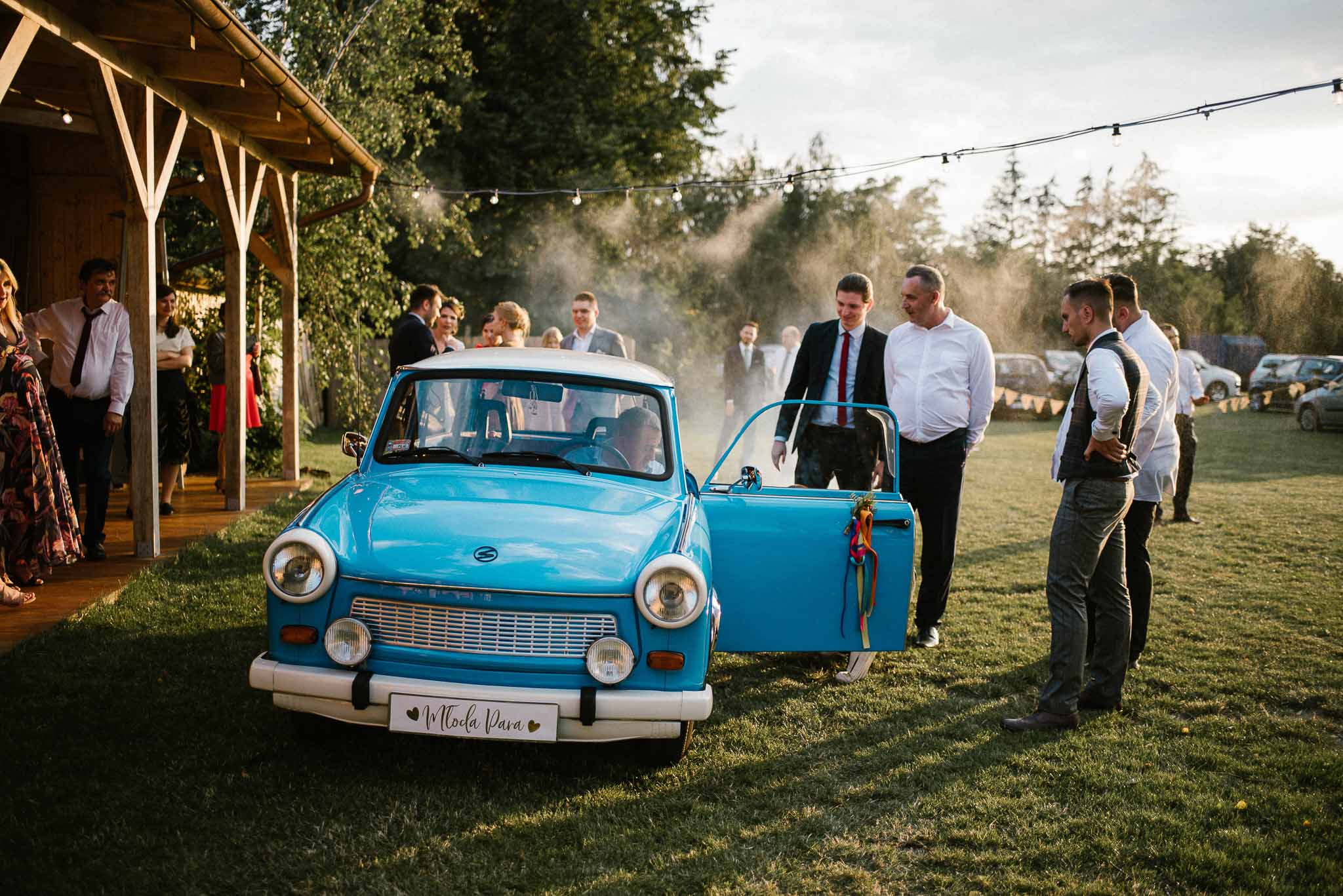 Goście weselni przy starym niebieskim trabancie - ślub w stodole Dyrkowo