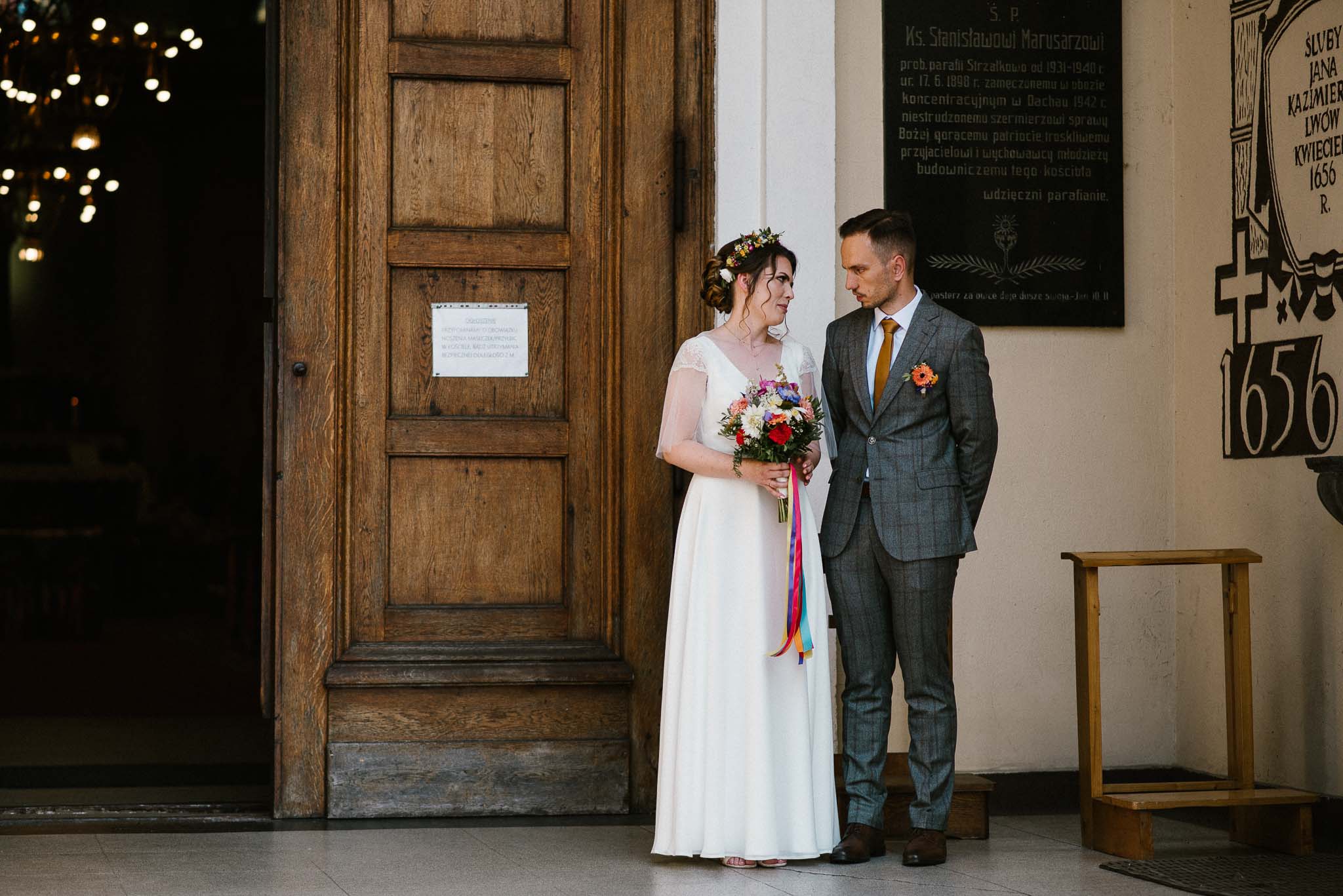 Para młoda stoi przed kościołem - ślub w stodole Dyrkowo