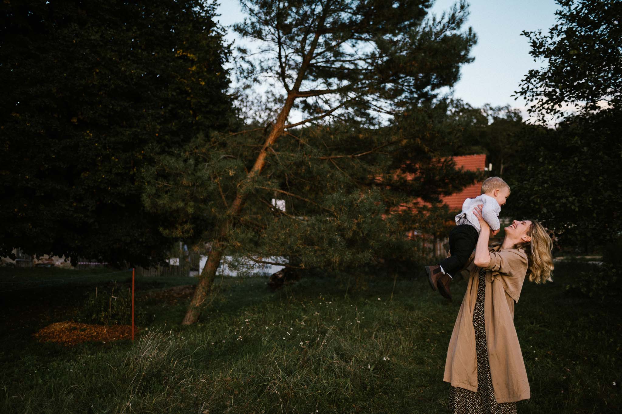 Mama trzyma synka na rękach i podrzuca do góry - sesja w plenerze jesienią w Poznaniu