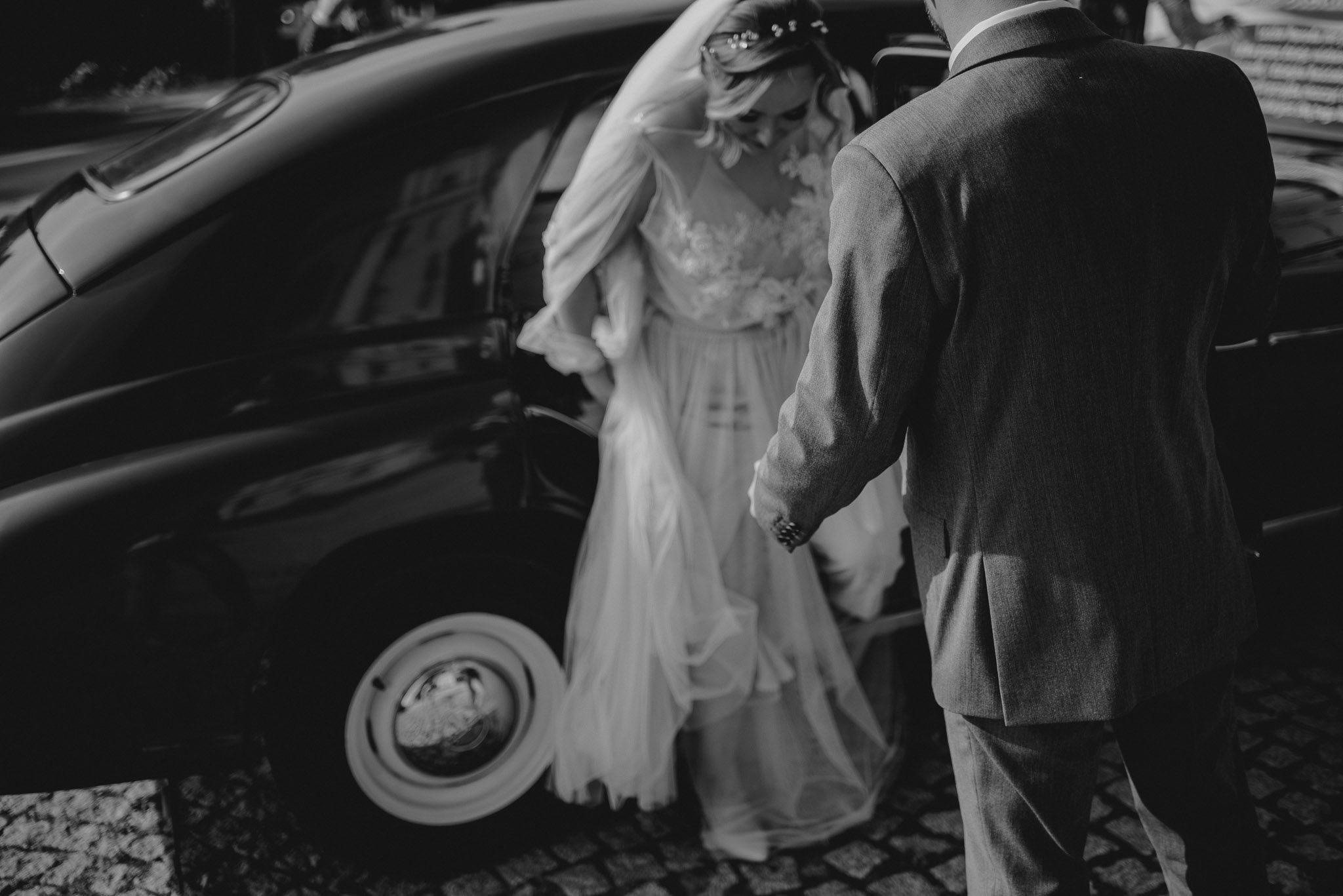 Panna młoda wysiada z bordowego samochodu - ślub w Biskupicach, Siedem Drzew