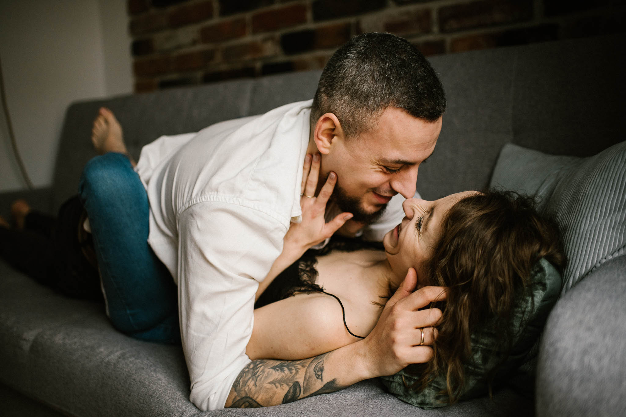 Mąż głaszcze żonę leżąc na kanapie - sesja sensualna pary lifestyle w Poznaniu