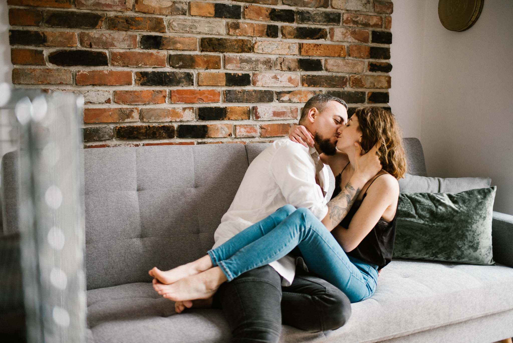Mąż całuje żonę na kanapie w salonie - sesja sensualna pary lifestyle w Poznaniu