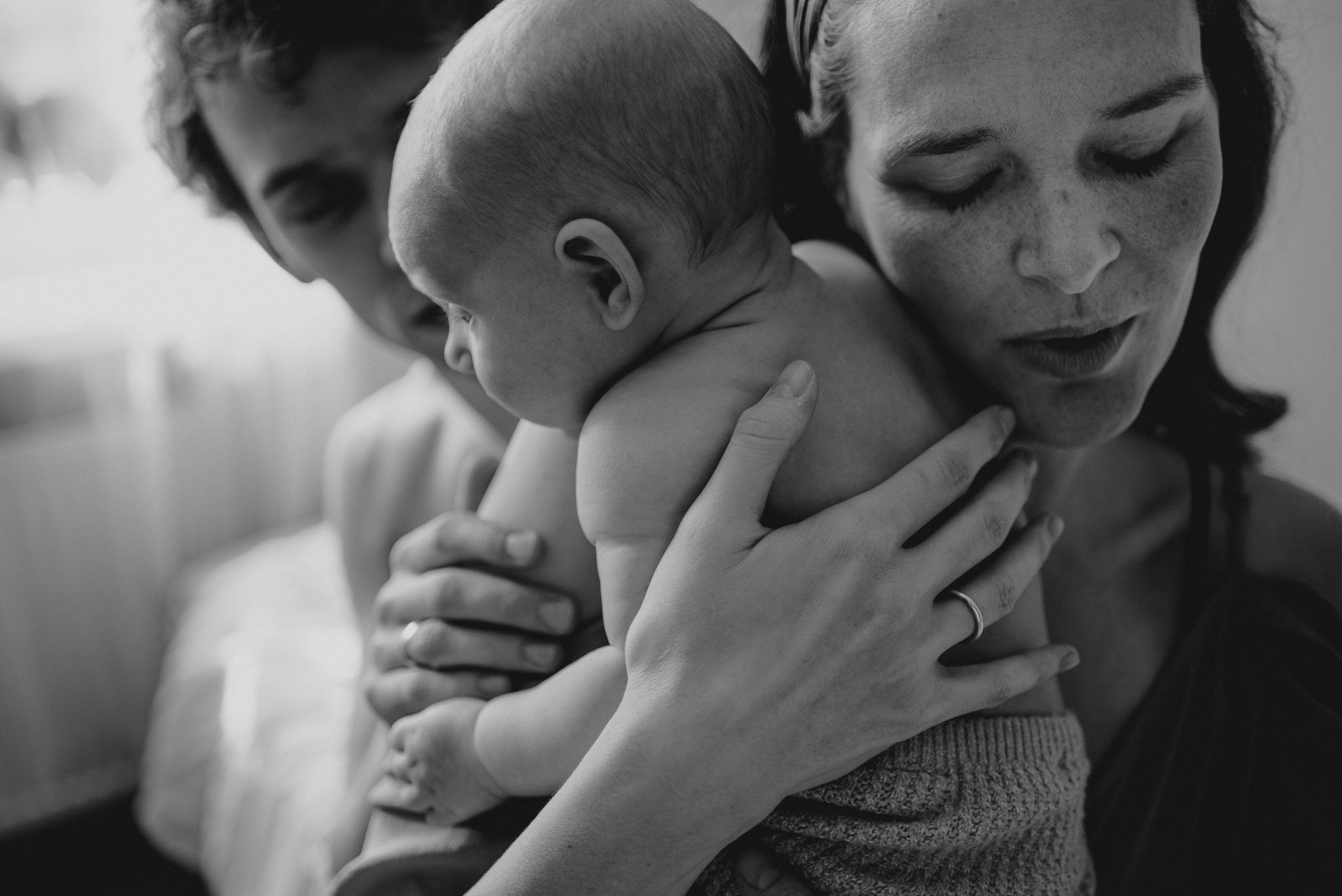 Rodzice przytulają niemowlę -Sesja niemowlęca lifestyle w domu Poznań