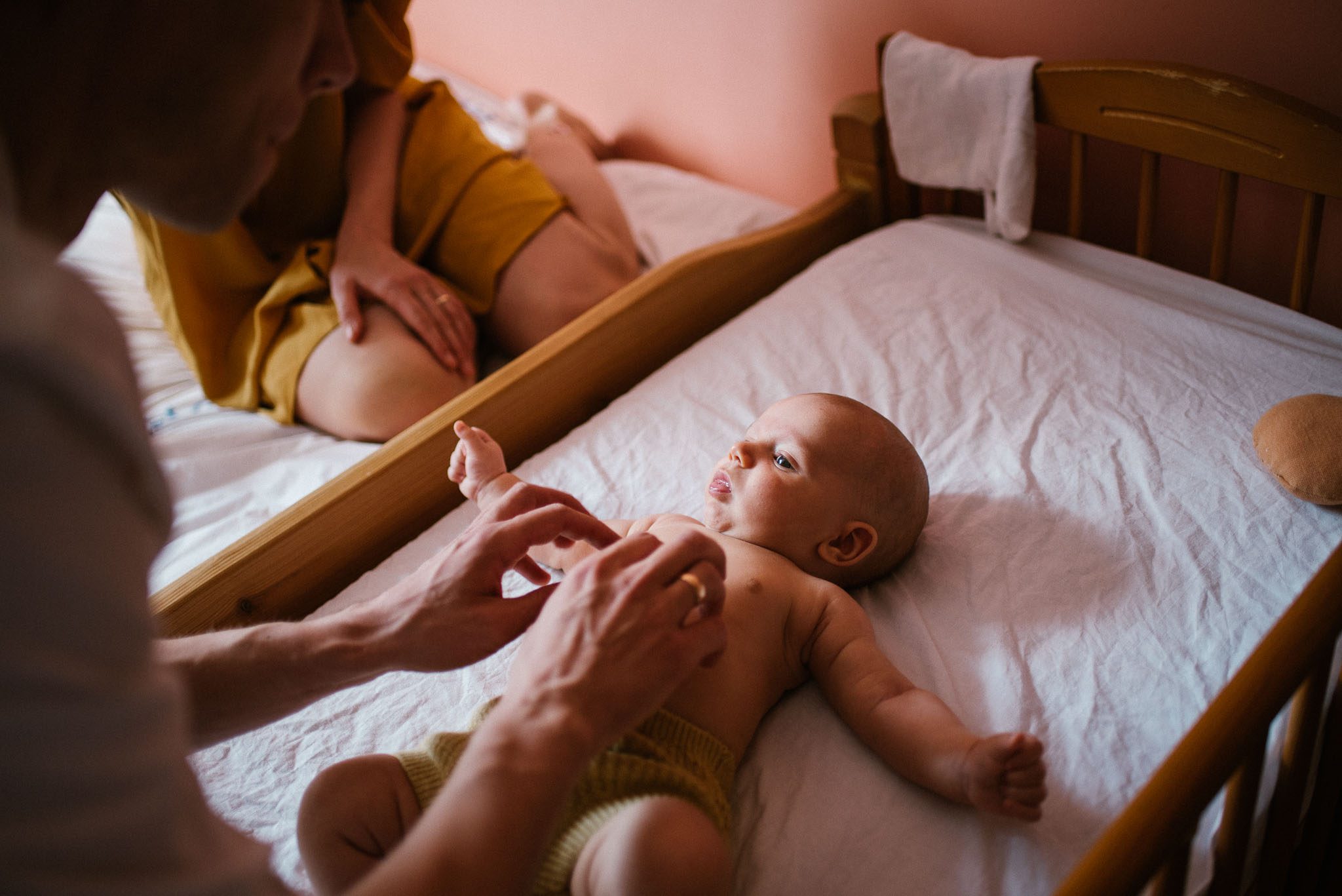 Rodzice budzą niemowlę w łóżeczku - sesja niemowlęca lifestyle w domu Poznań
