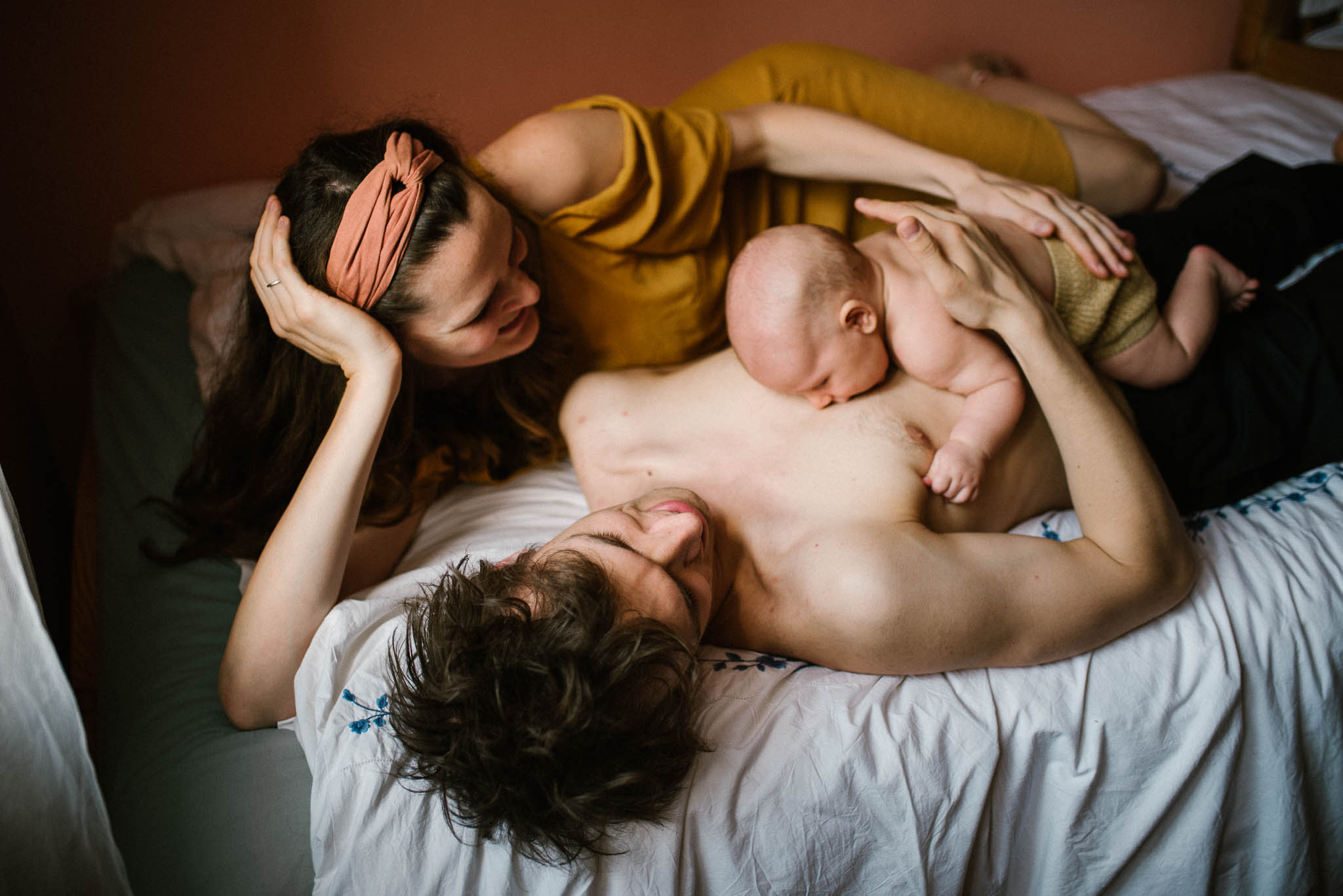 Mama tata i niemowę leżą razem w łóżku, dziecko na tacie - sesja niemowlęca lifestyle w domu Poznań