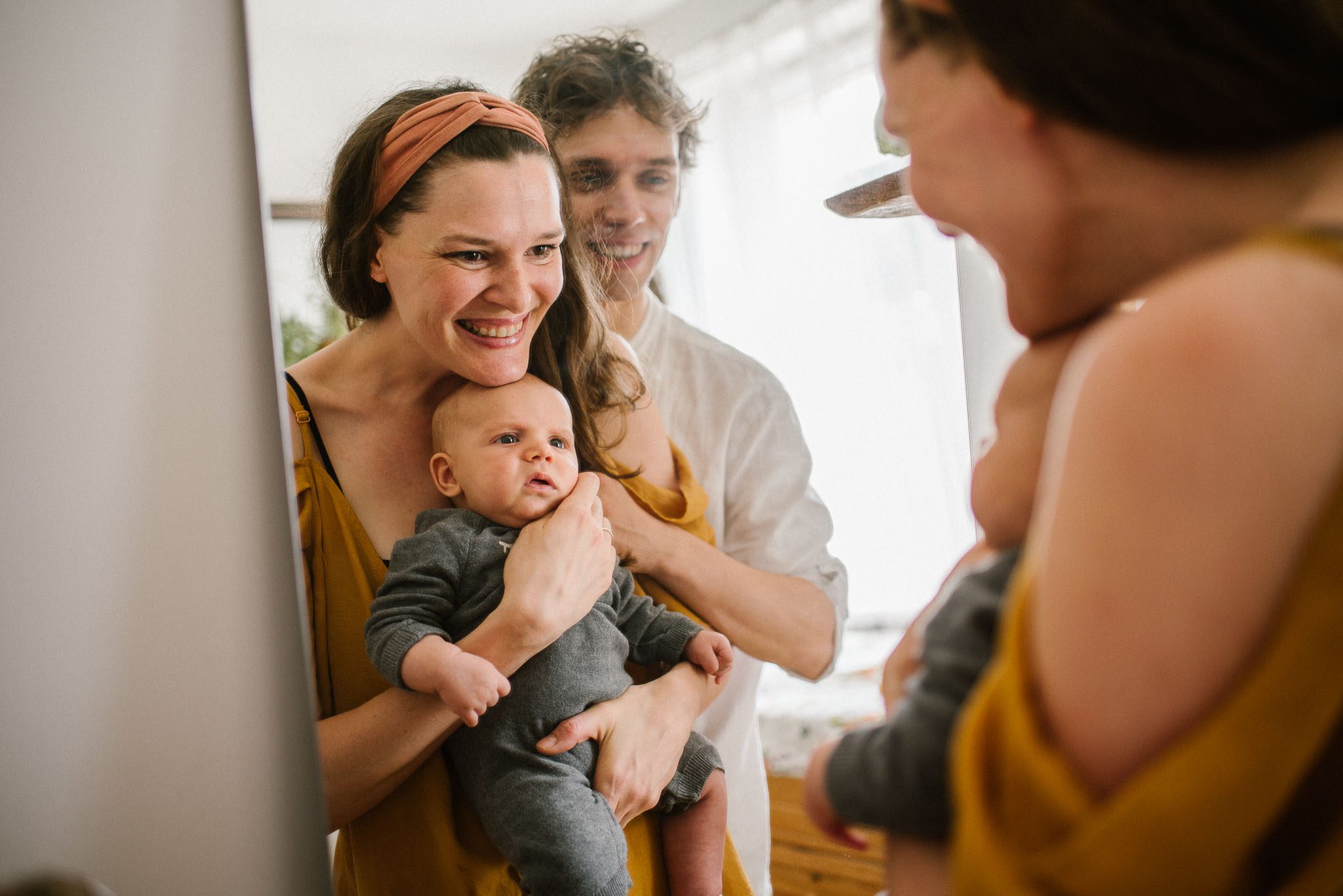 Rodzina przegląda się z niemowlęciem w lustrze - Sesja niemowlęca lifestyle w domu Poznań